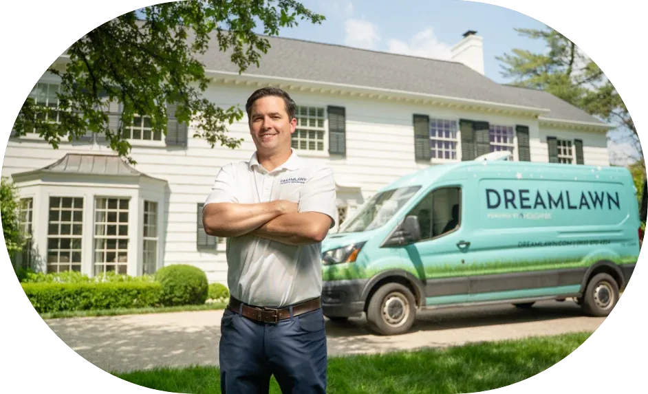 DreamLawn lawn care technician standing beside a branded company service van